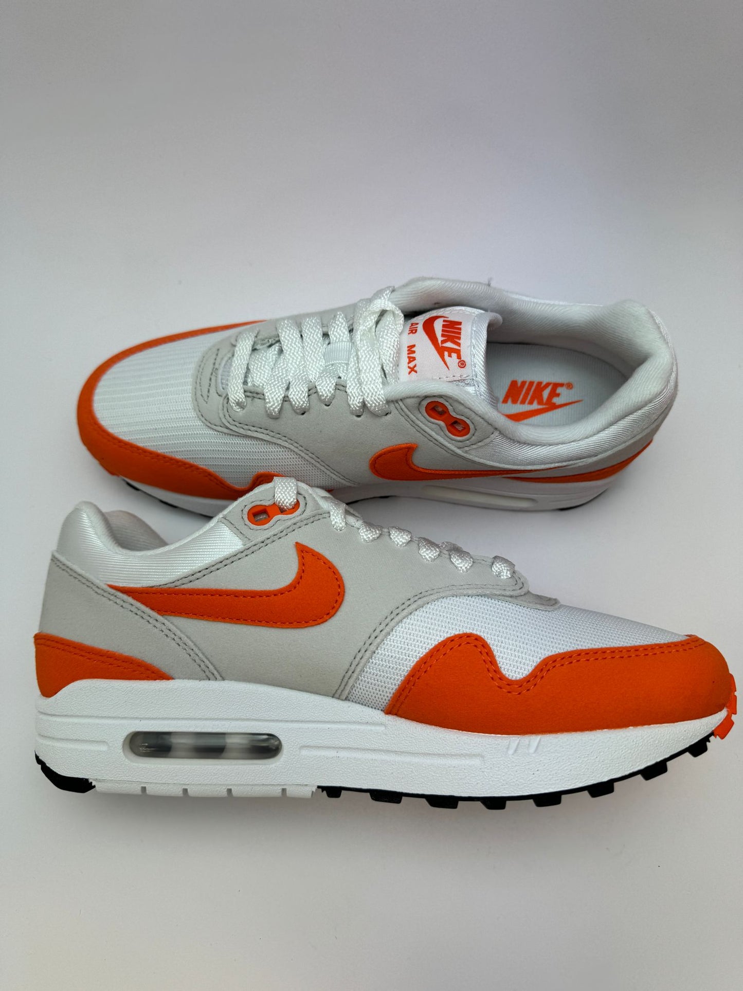 Nike Air Max 1 Safety Orange – linke Außenseite mit Safety‑Orange-Swoosh und hellgrauen Overlays