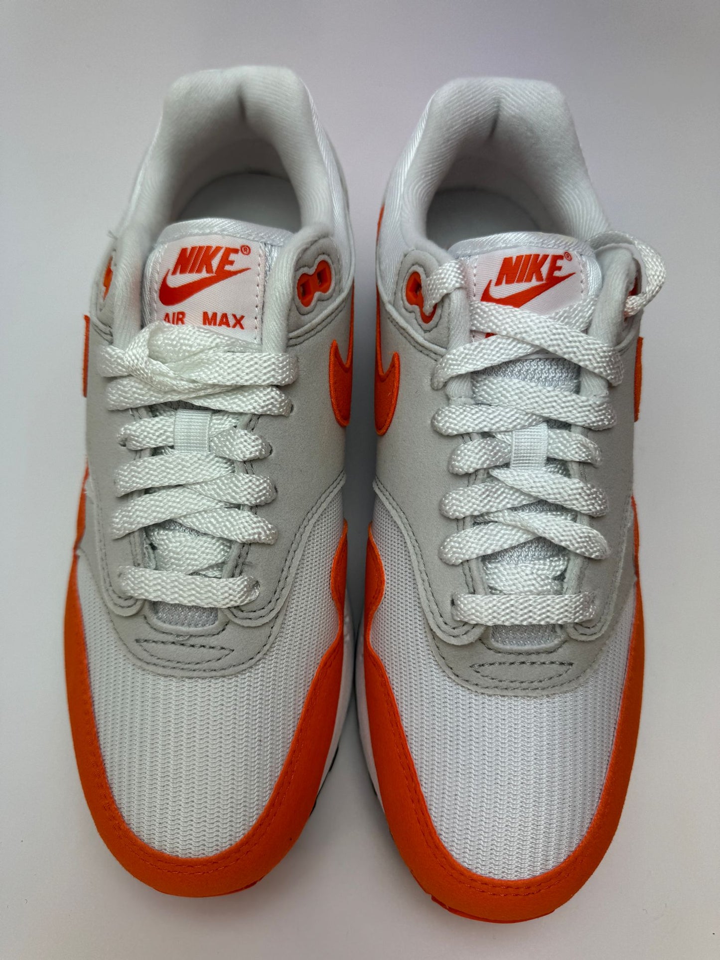 Rückansicht des Sneakers – Nike Air Max 1 Safety Orange mit Air Max-Fersenbranding in Orange und schwarzer Außensohle