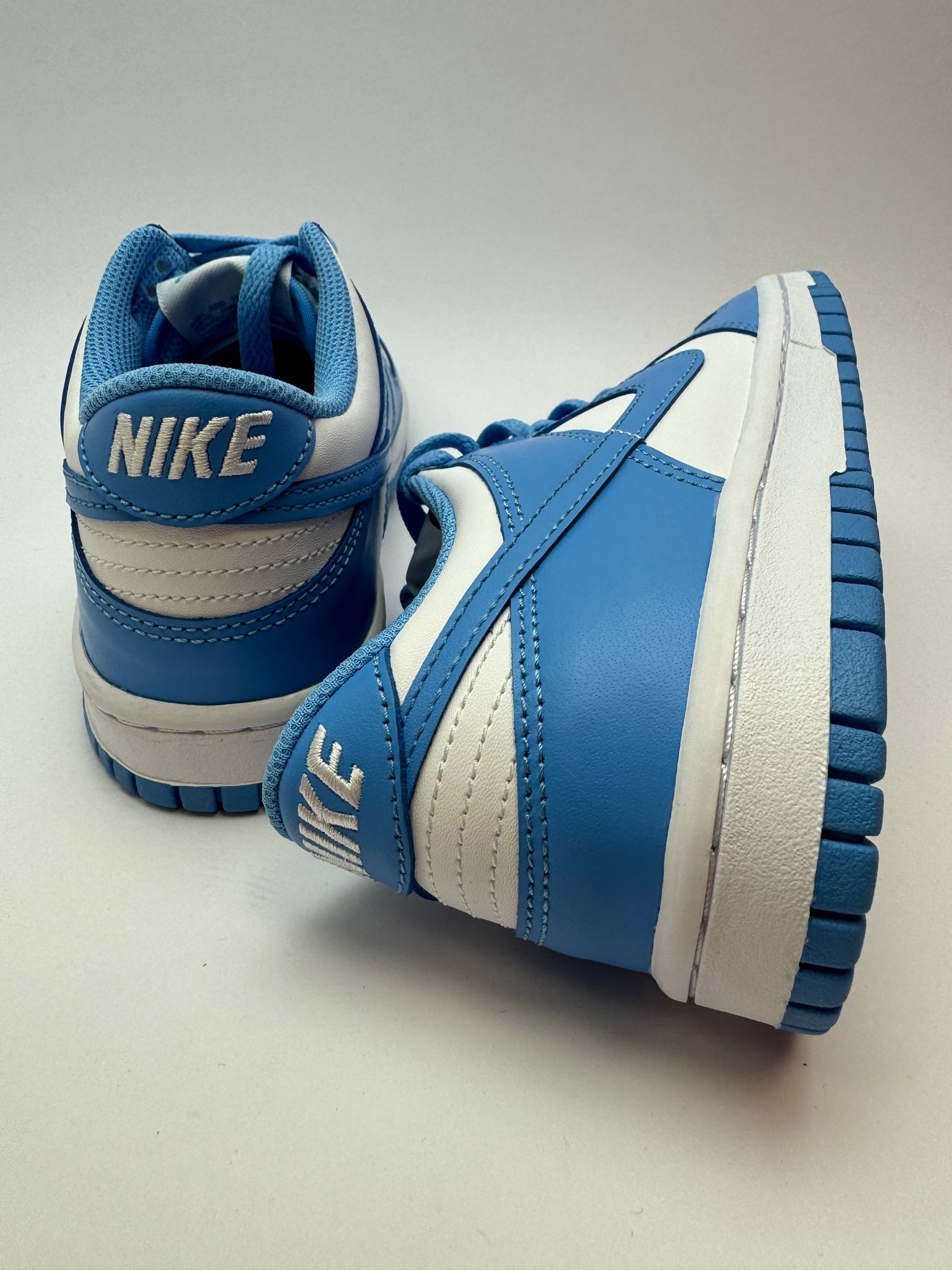 Rückansicht des Sneakers – Nike Dunk Low UNC mit grünem, exponiertem Foam-Zungenrand und rotem Tag-Detail
