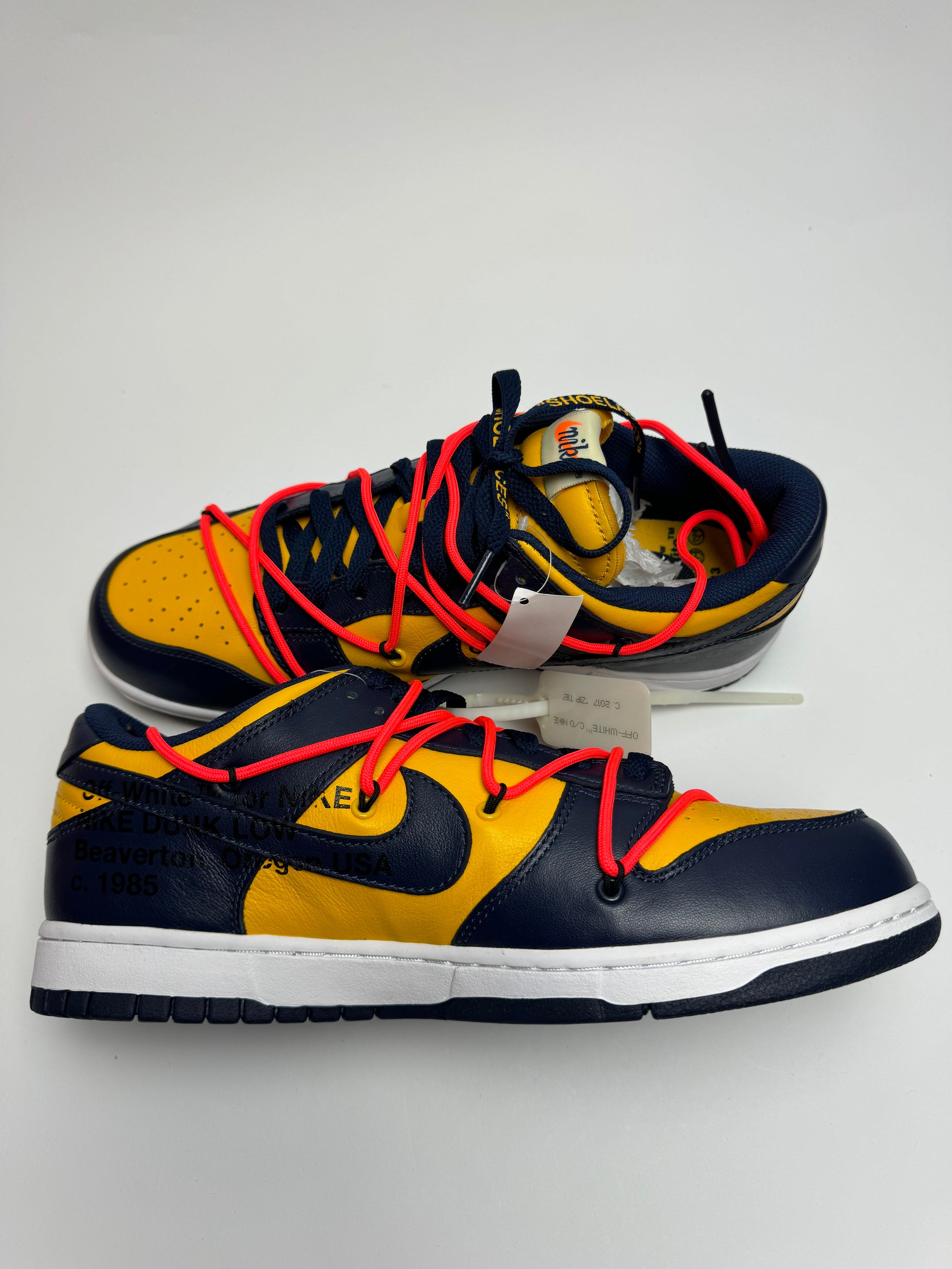 Off‑White Dunk Low University Gold – linke Außenseite mit weißem Swoosh und orangefarbenem Flag-Label am Overlay