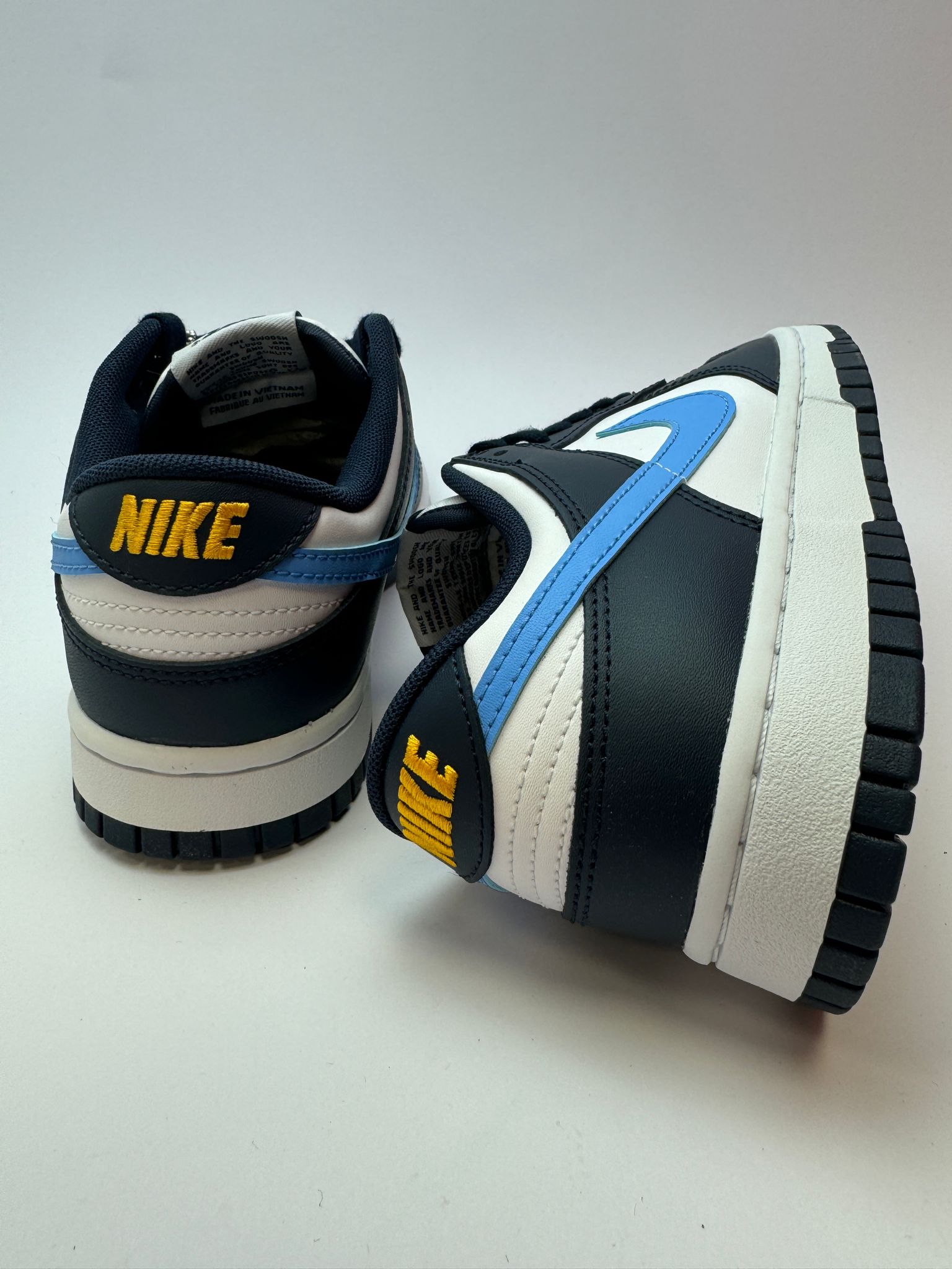 Rückansicht des Sneakers – Nike Dunk Low Midnight Navy University Blue mit goldfarbenem 'NIKE'-Logo auf dem Heel-Tab