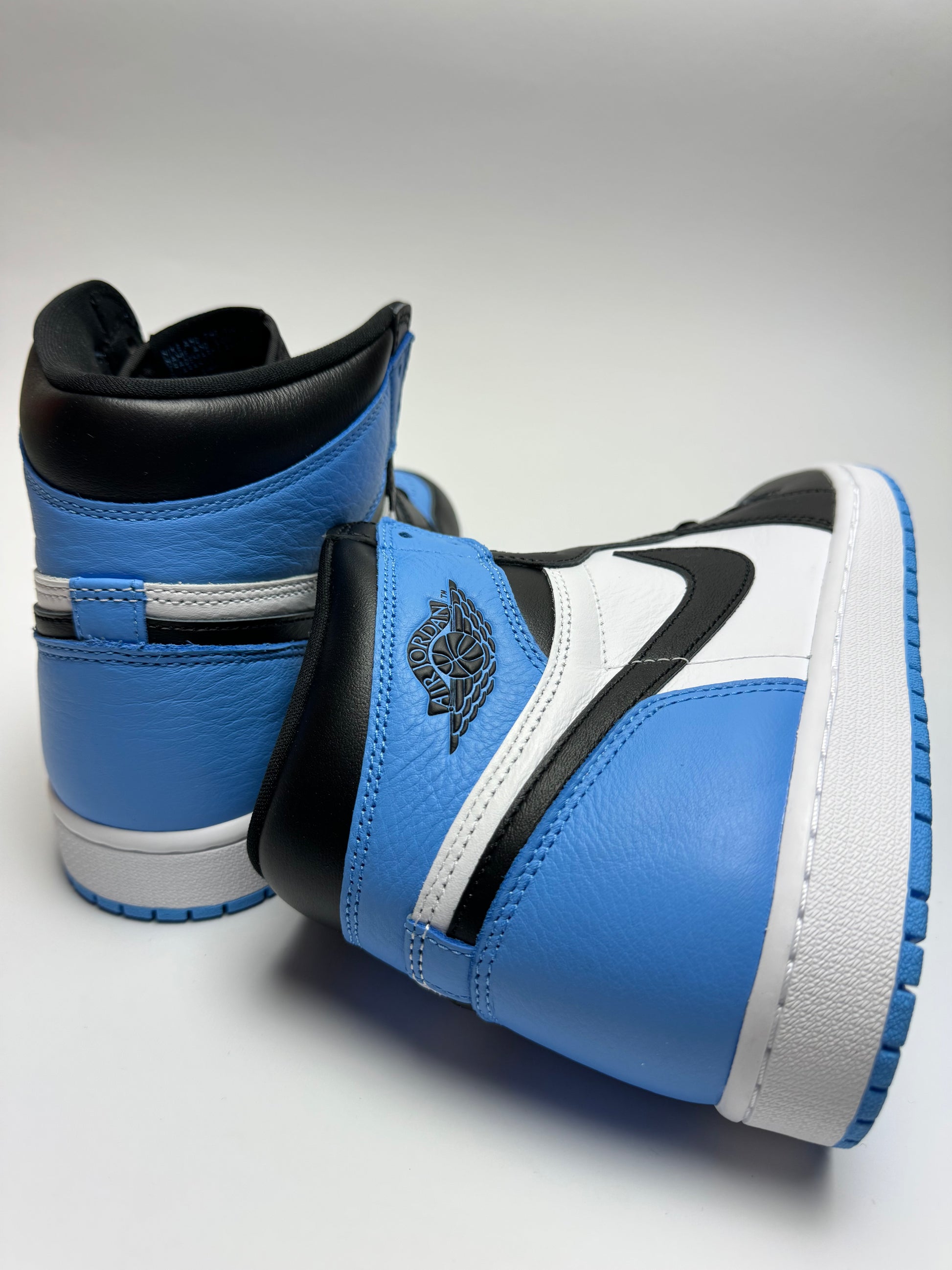 Rückansicht des Sneakers – Air Jordan 1 High UNC Toe mit gepolstertem Heel‑Tab und Wings‑Logo in Schwarz