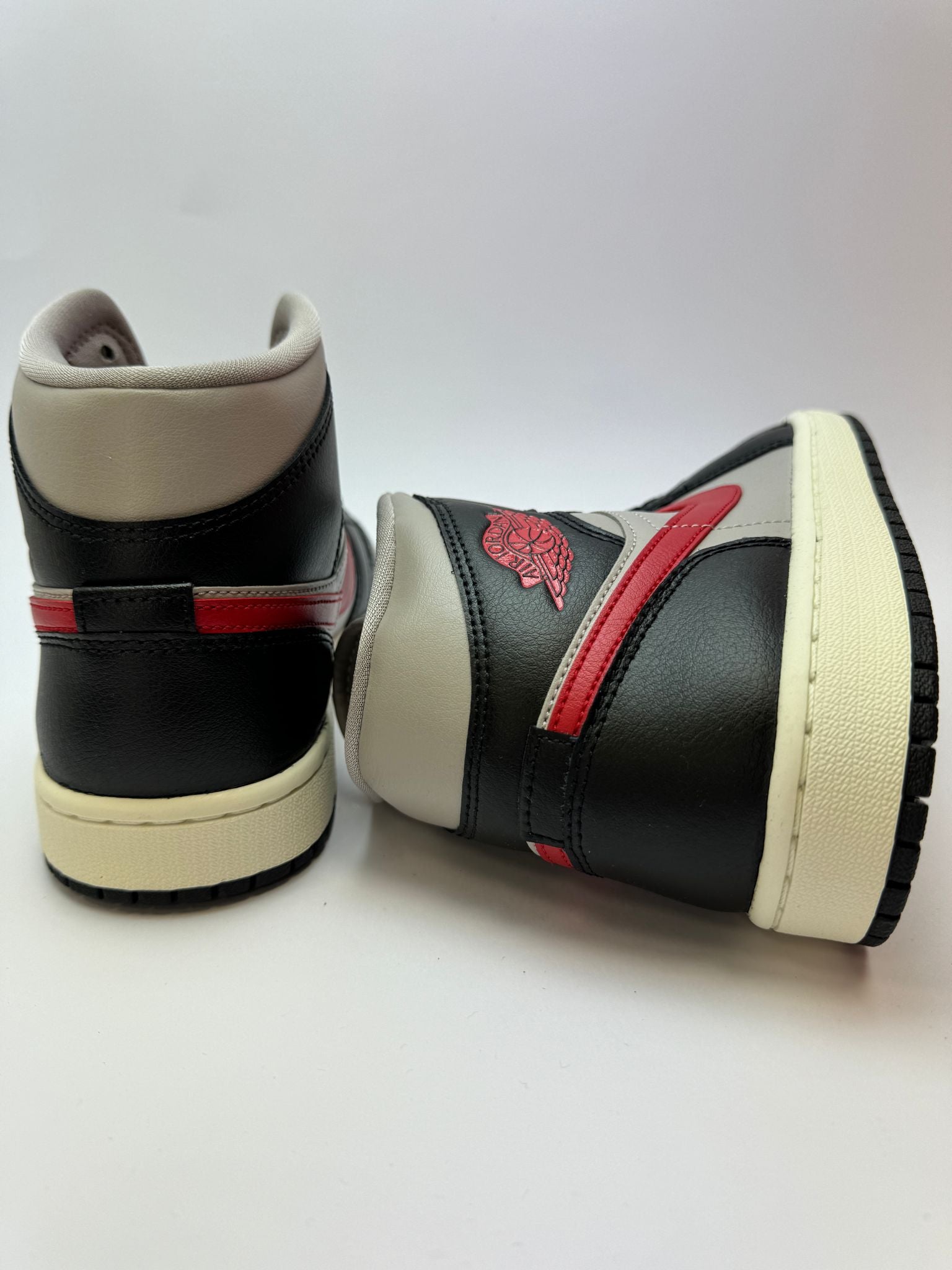 Rückansicht des Sneakers – Jordan 1 Mid Black/College Grey–Gym Red mit gepolstertem Heel-Tab und Nike‑Wings-Logo