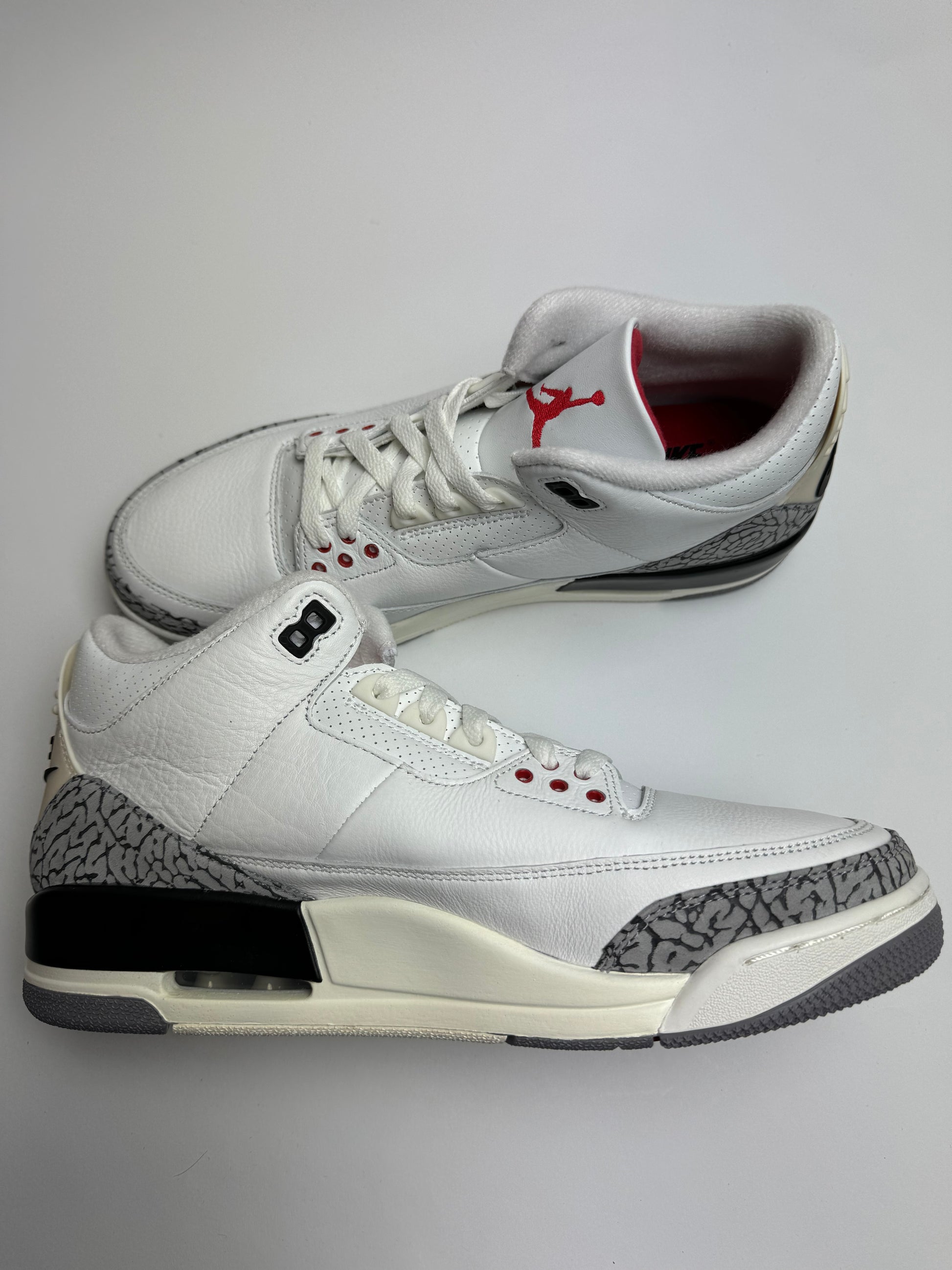 Air Jordan 3 White Cement Reimagined – linke Seitenansicht mit Fire Red Eyelets, schwarzem Swoosh und Vintage‑Look Heel-Tab