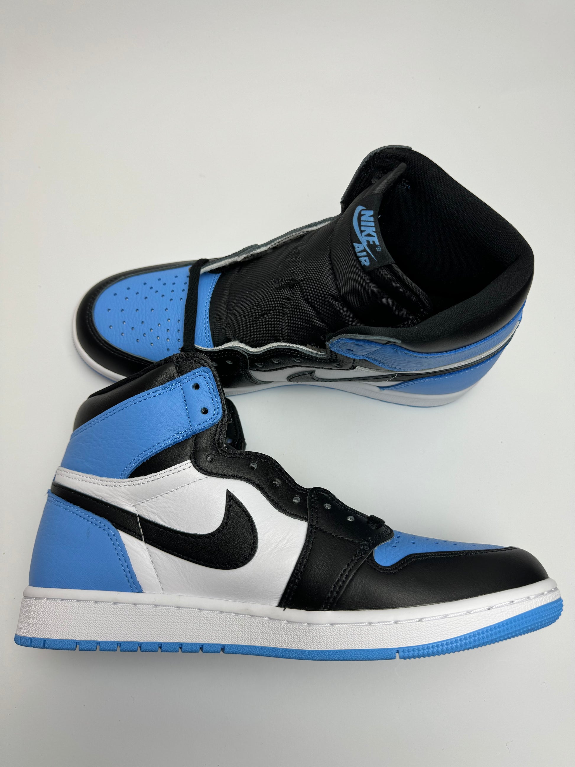 Air Jordan 1 High UNC Toe – linke Außenseite mit schwarzem Swoosh, weißem Middle‑Panel und University‑Blue‑Ferse
