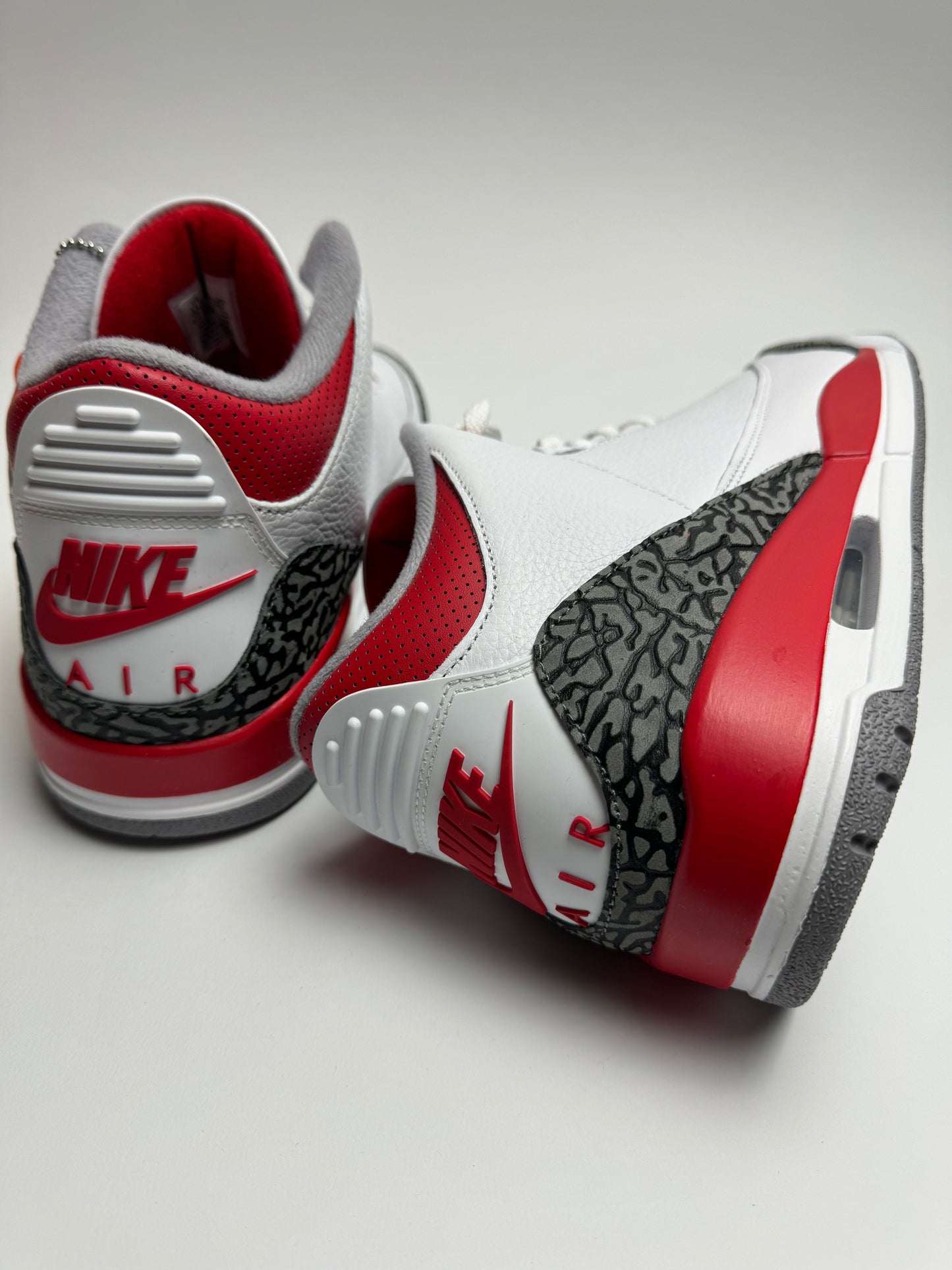 Rückansicht des Sneakers – weiße Ferse mit ‚NIKE AIR‘ Branding in Fire Red und sandfarbenem Elefanten-Print