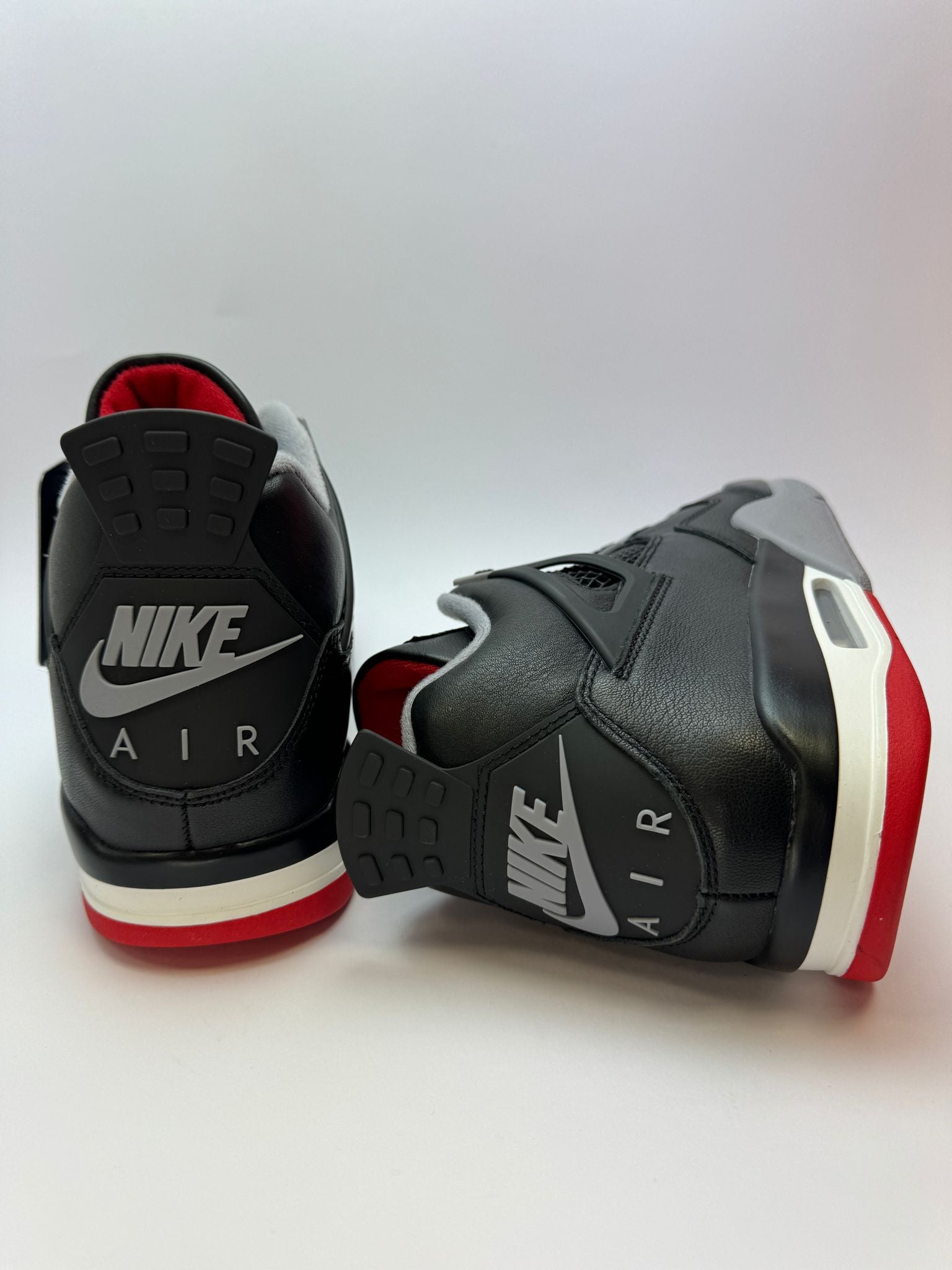 Detailansicht der Zunge – Air Jordan 4 Retro Bred Reimagined mit rotem Jumpman-Logo auf schwarzem Leder