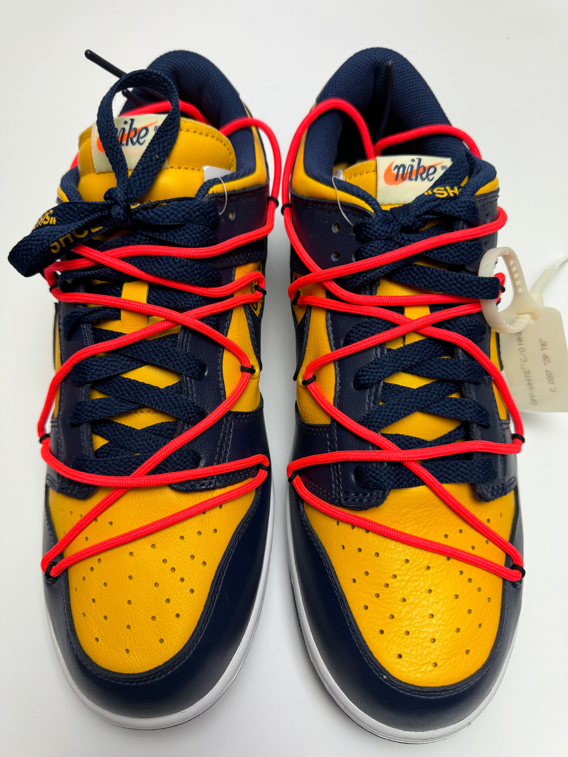 Detailansicht der Zunge – Off‑White Dunk Low University Gold mit rauh geschnittenem Schaumstoff-Zungenrand und roter Zip‑Tie