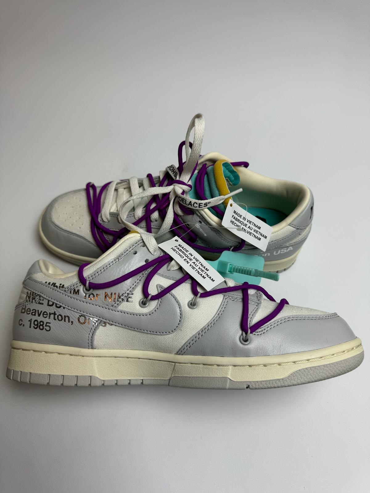 Off‑White Nike Dunk Low Lot 21 – linke Außenseite mit grauem Swoosh und Helvetica‑Branding unter dem Logo
