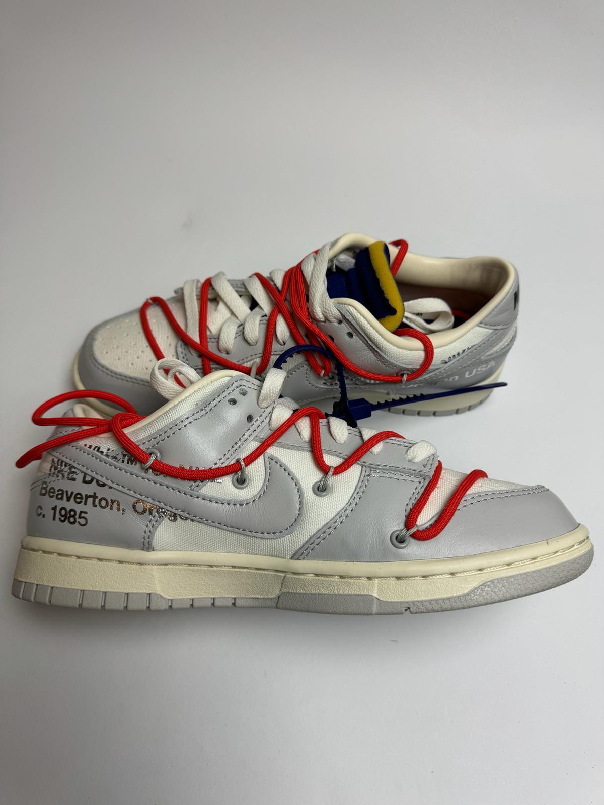 Off‑White Nike Dunk Low Lot 23 – linke Außenseite mit grauem Swoosh und typischem Helvetica‑Branding unter dem Logo
