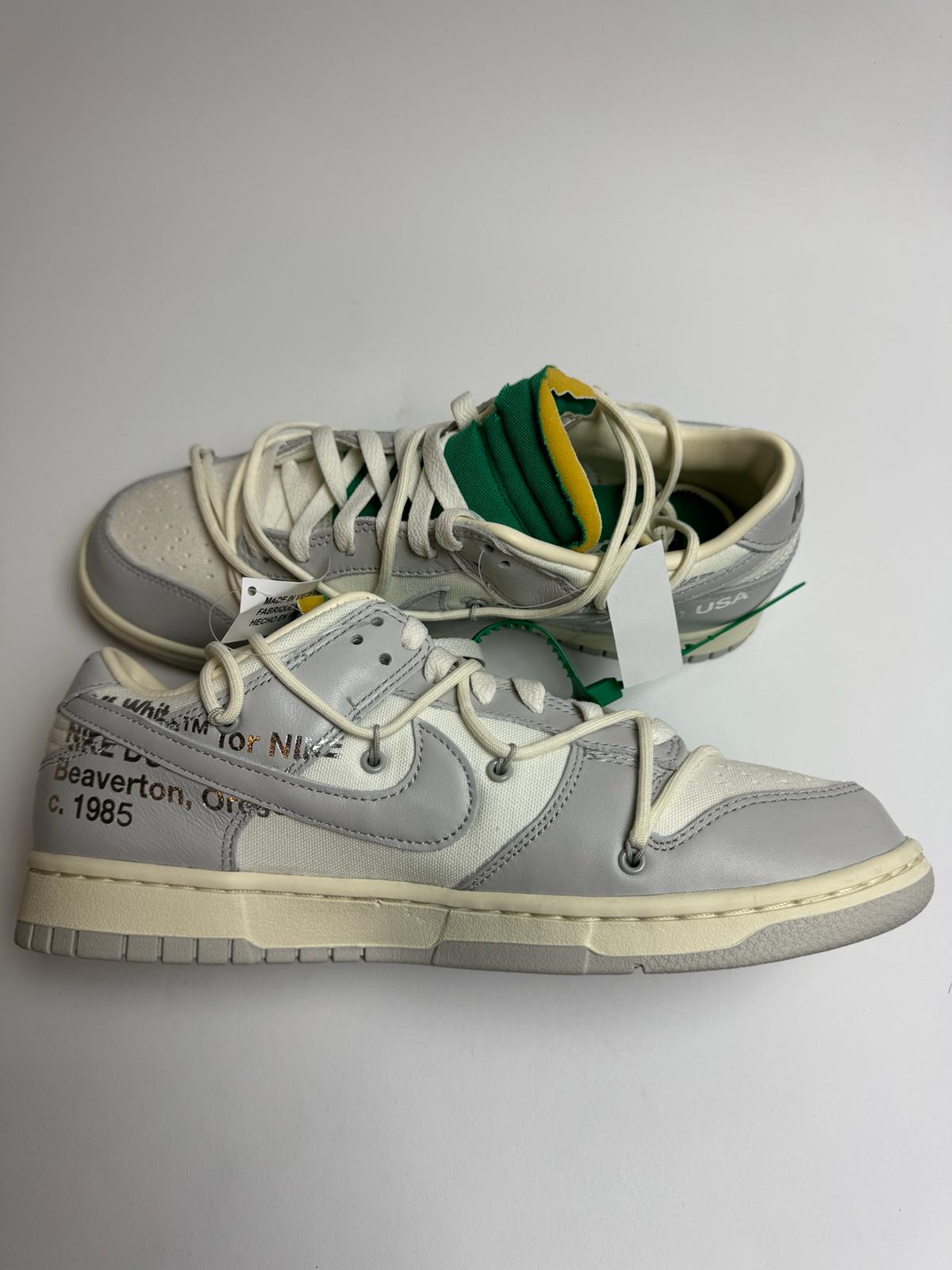 Off-White Nike Dunk Low Lot 25 – linke Außenseite mit grauem Swoosh und dezenter Helvetica-Branding unter dem Logo