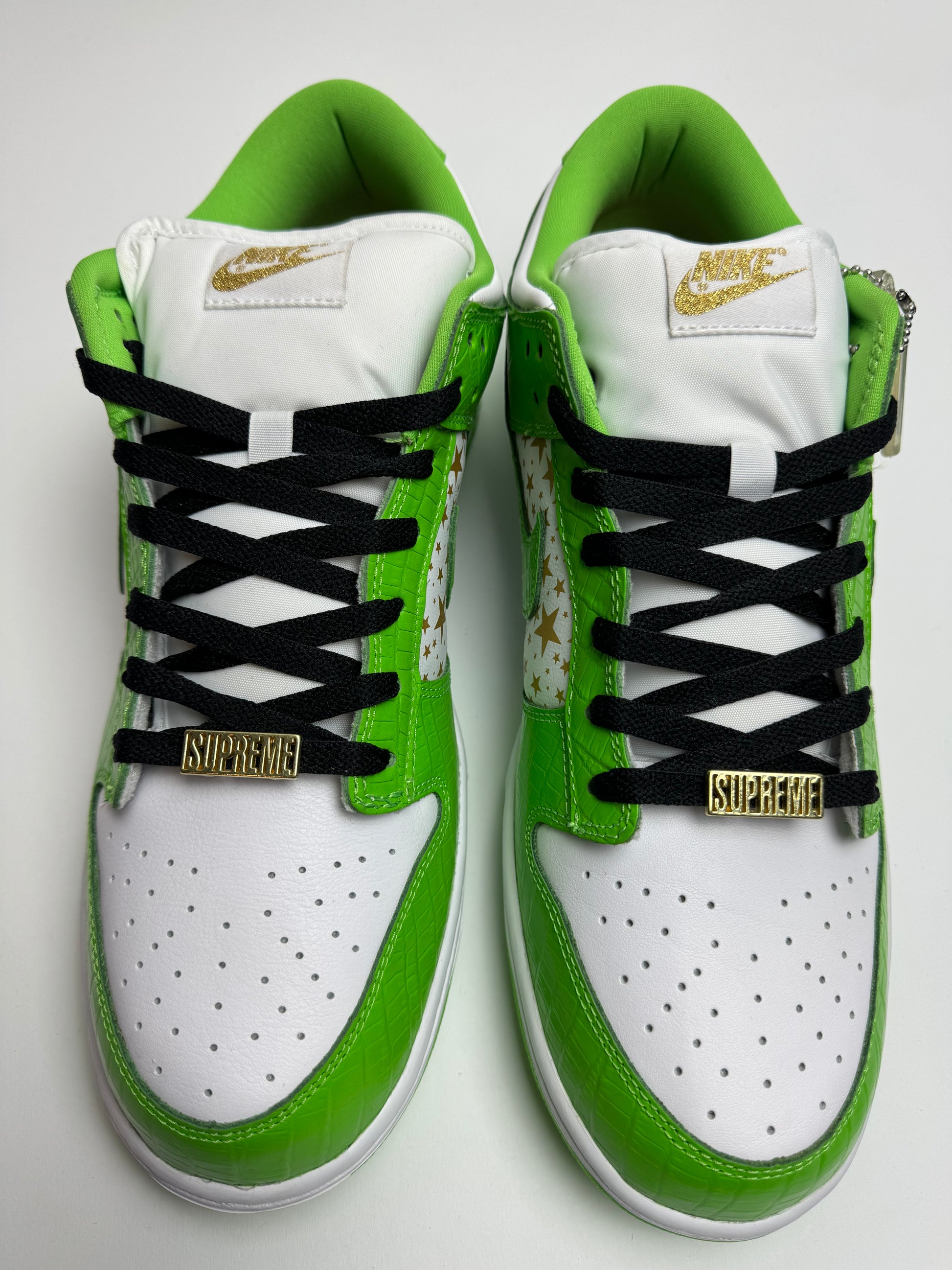 Detailansicht der Zunge – Nike SB Dunk Low Supreme Mean Green mit gepolsterter SB-Zunge, co-branded Supreme-Nike Label und goldener Lace‑Jewel