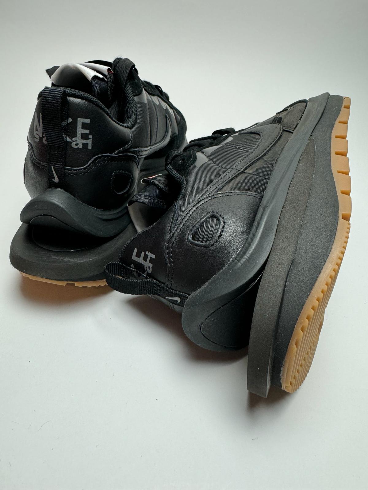 Rückansicht des Sneakers – Nike Vaporwaffle Sacai Black/Gum mit grünem, exponiertem Foam-Zungenrand und rotem Tag-Detail