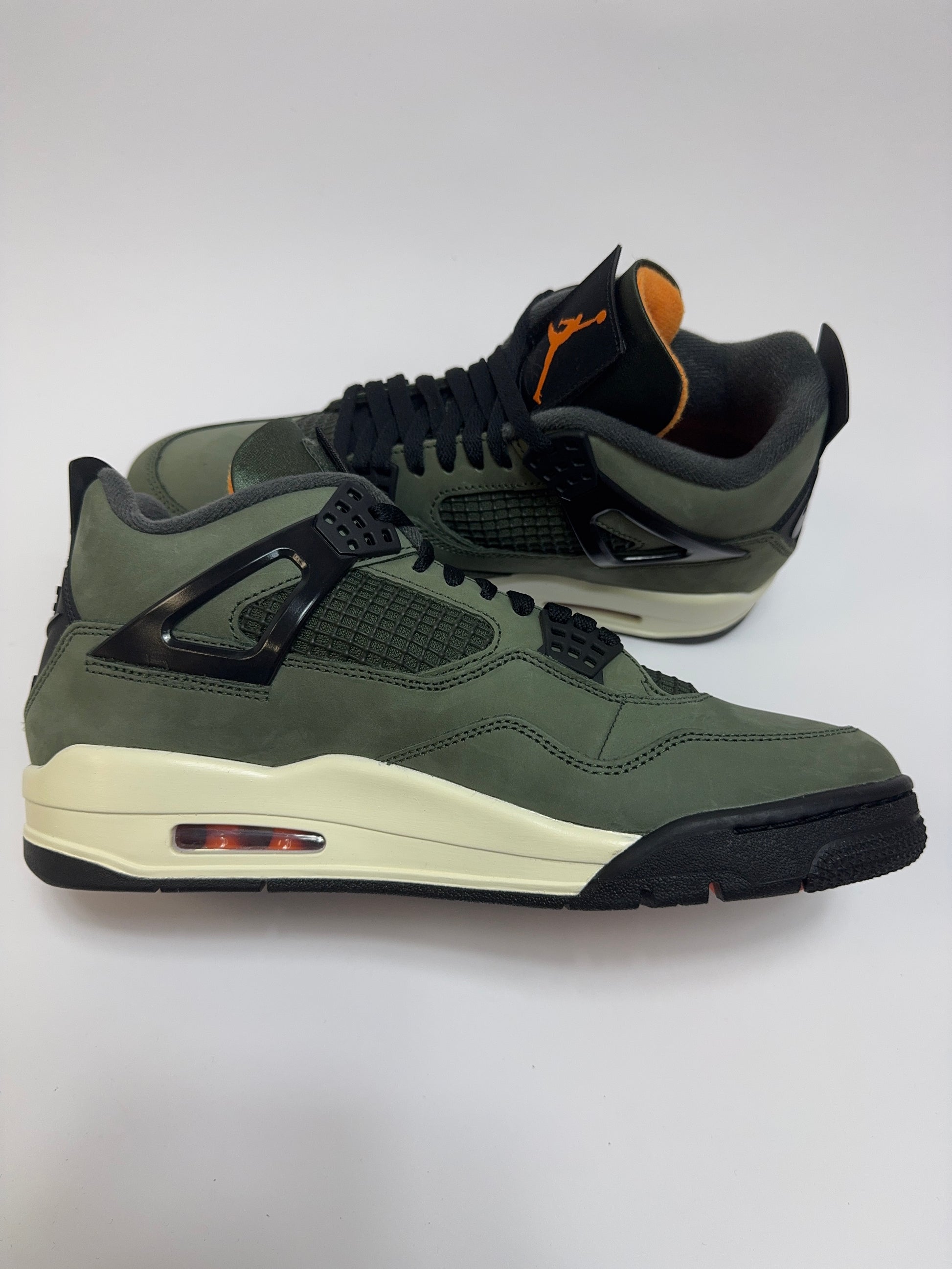 Air Jordan 4 Undefeated 2025 linke Ansicht mit Clementine Details, schwarzer Overlays und Sail Midsole