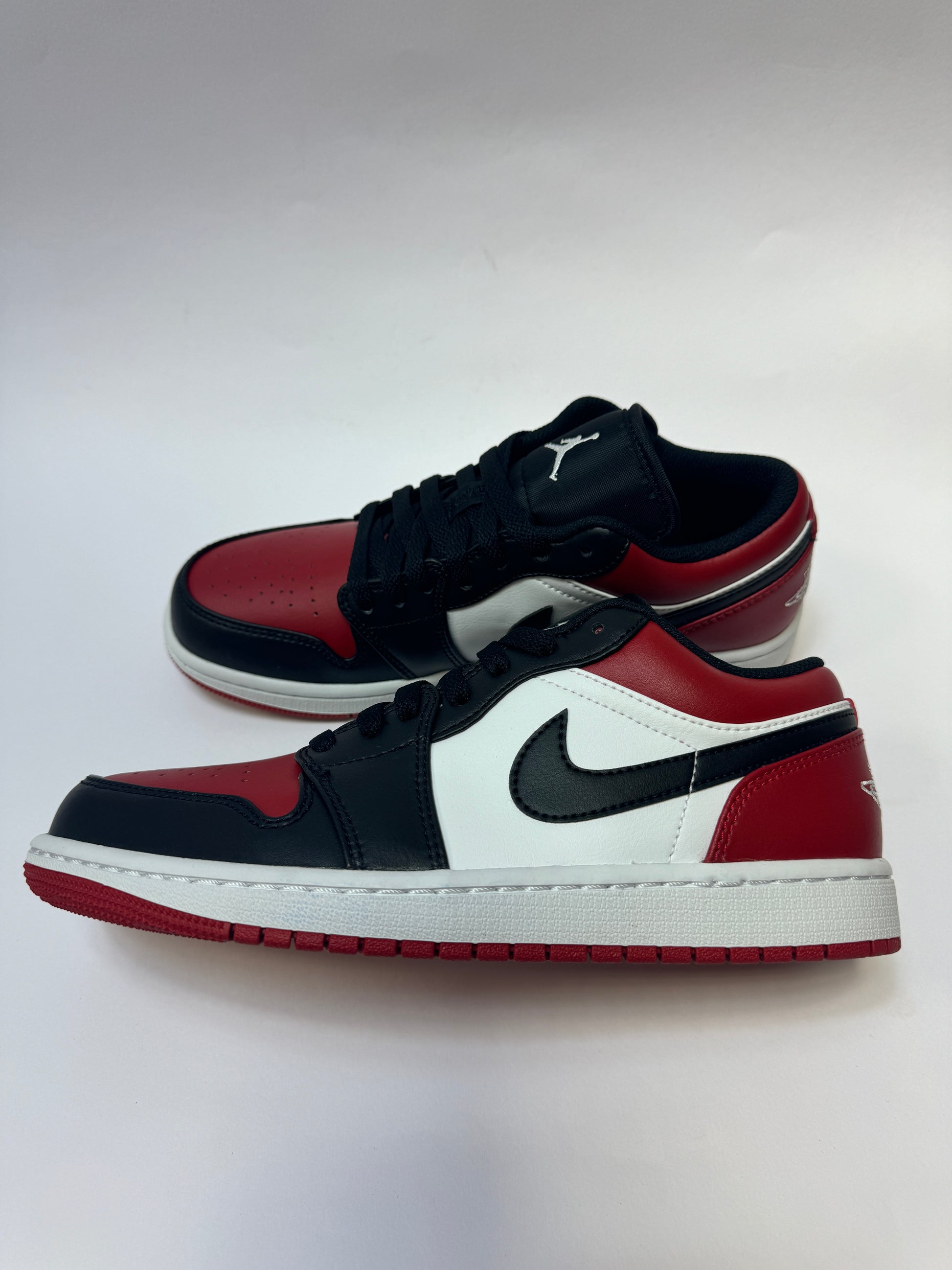 Seitenansicht des Air Jordan 1 Low Bred Toe mit klassischem schwarz-weiß-rotem Leder-Upper.