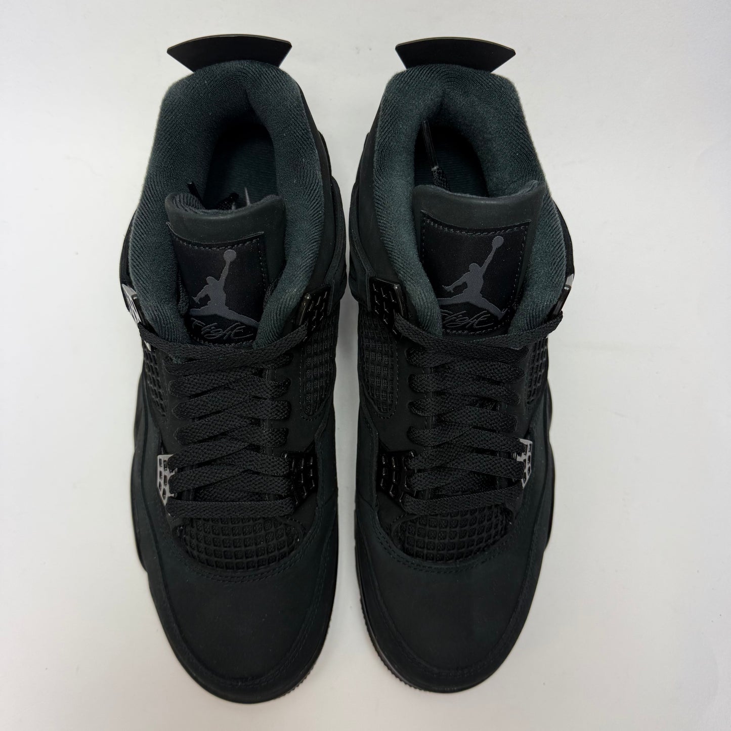 Draufsicht auf beide Air Jordan 4 Black Cat 2025 mit schwarzer Schnürung und monochromem Design