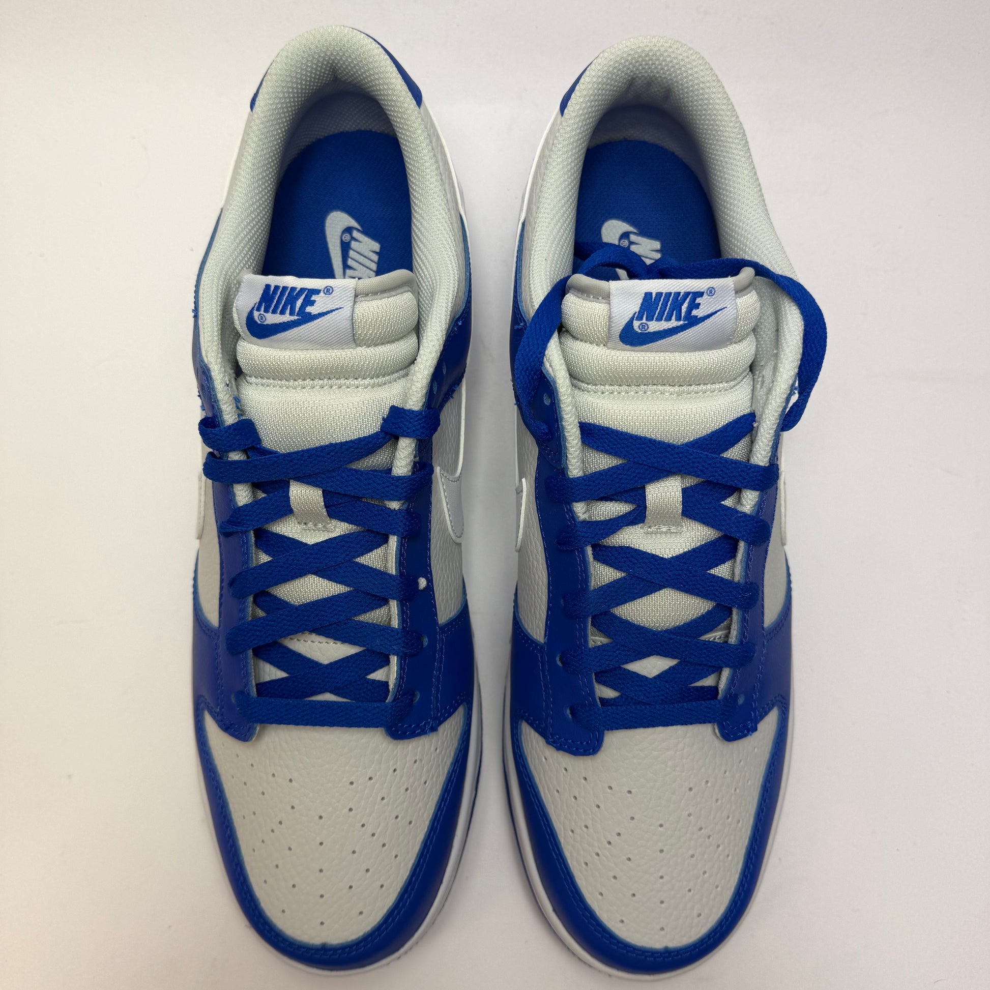 Draufsicht auf beide Nike Dunk Low Racer Blue Photon Dust mit weißer Schnürung und perforierter Toe Box