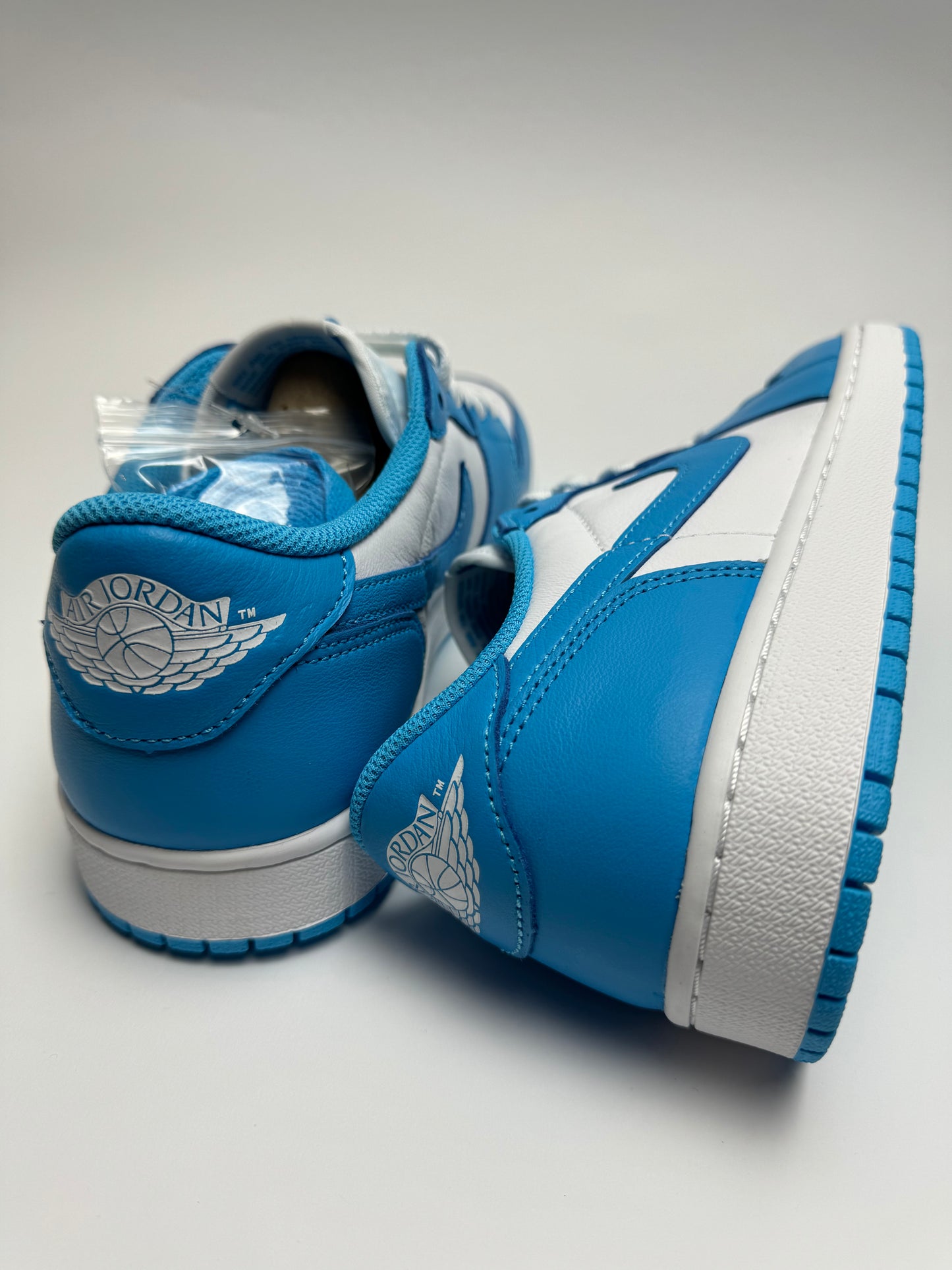 Rückansicht des Sneakers – UNC Low mit Wings‑Logo an der Ferse und dunkelblau gefärbtem Leder-Patch