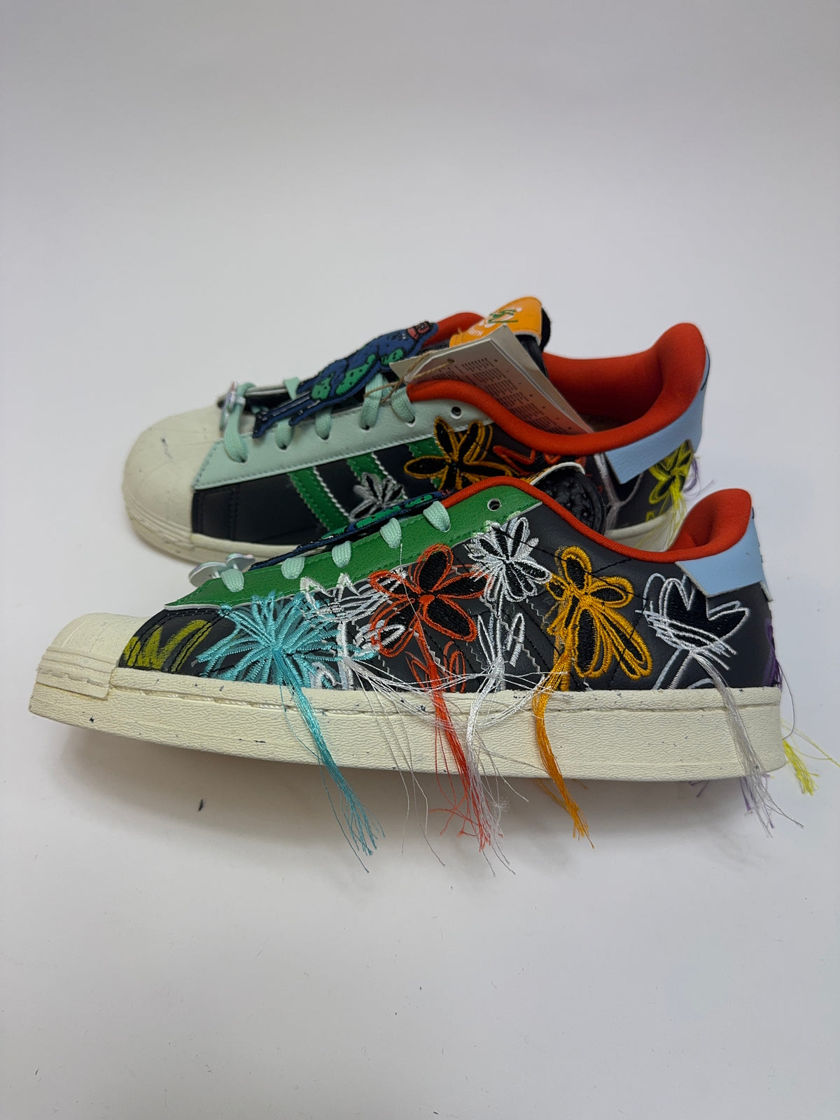 Seitenansicht des Sean Wotherspoon x adidas Superstar SuperEarth Black mit schwarzem Upper und farbenfrohen floralen Stickereien