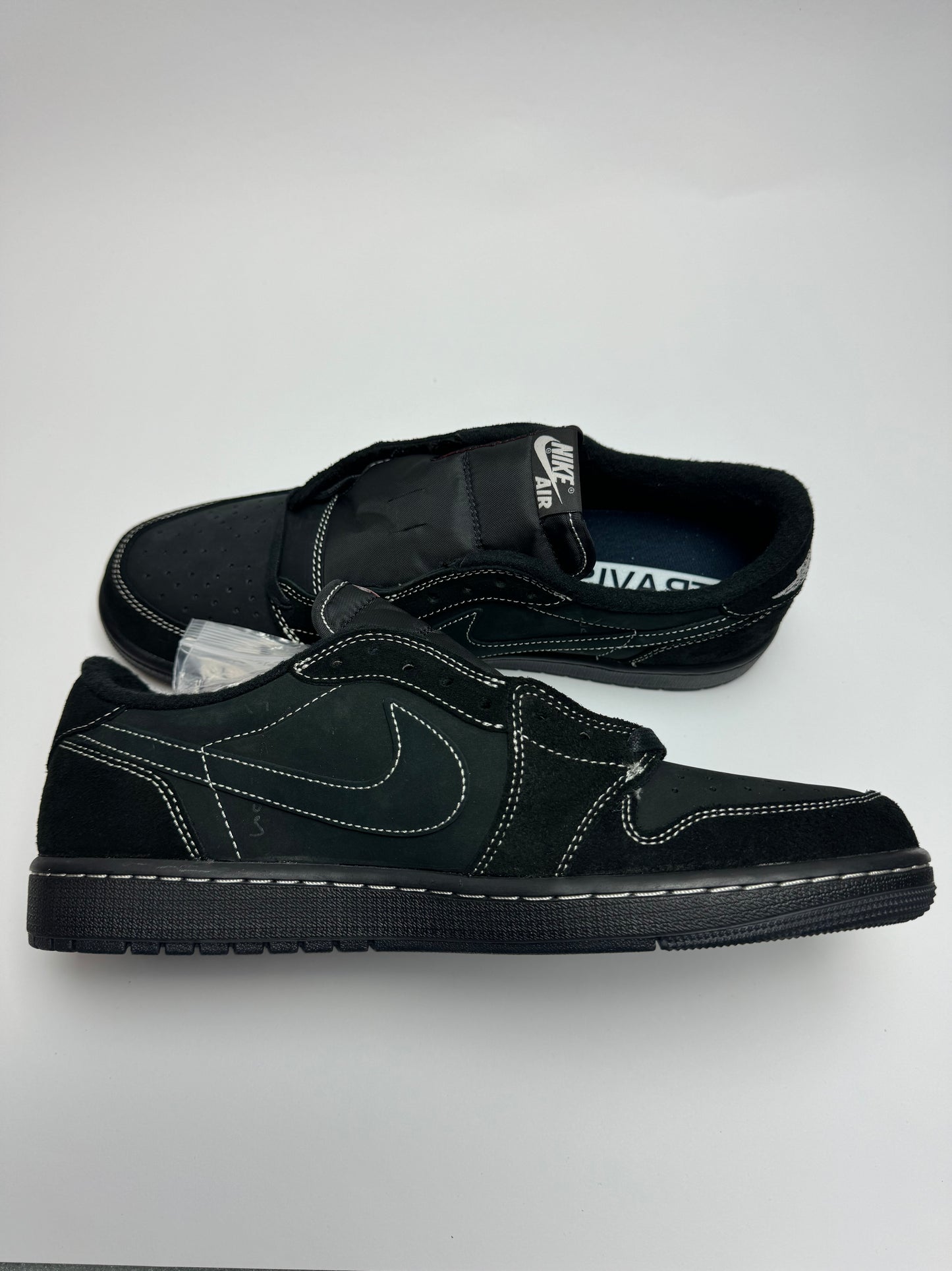 Travis Scott AJ1 Low Black Phantom – linke Außenseite mit zurückgesetztem Swoosh und kontrastreicher weißer Ziernaht