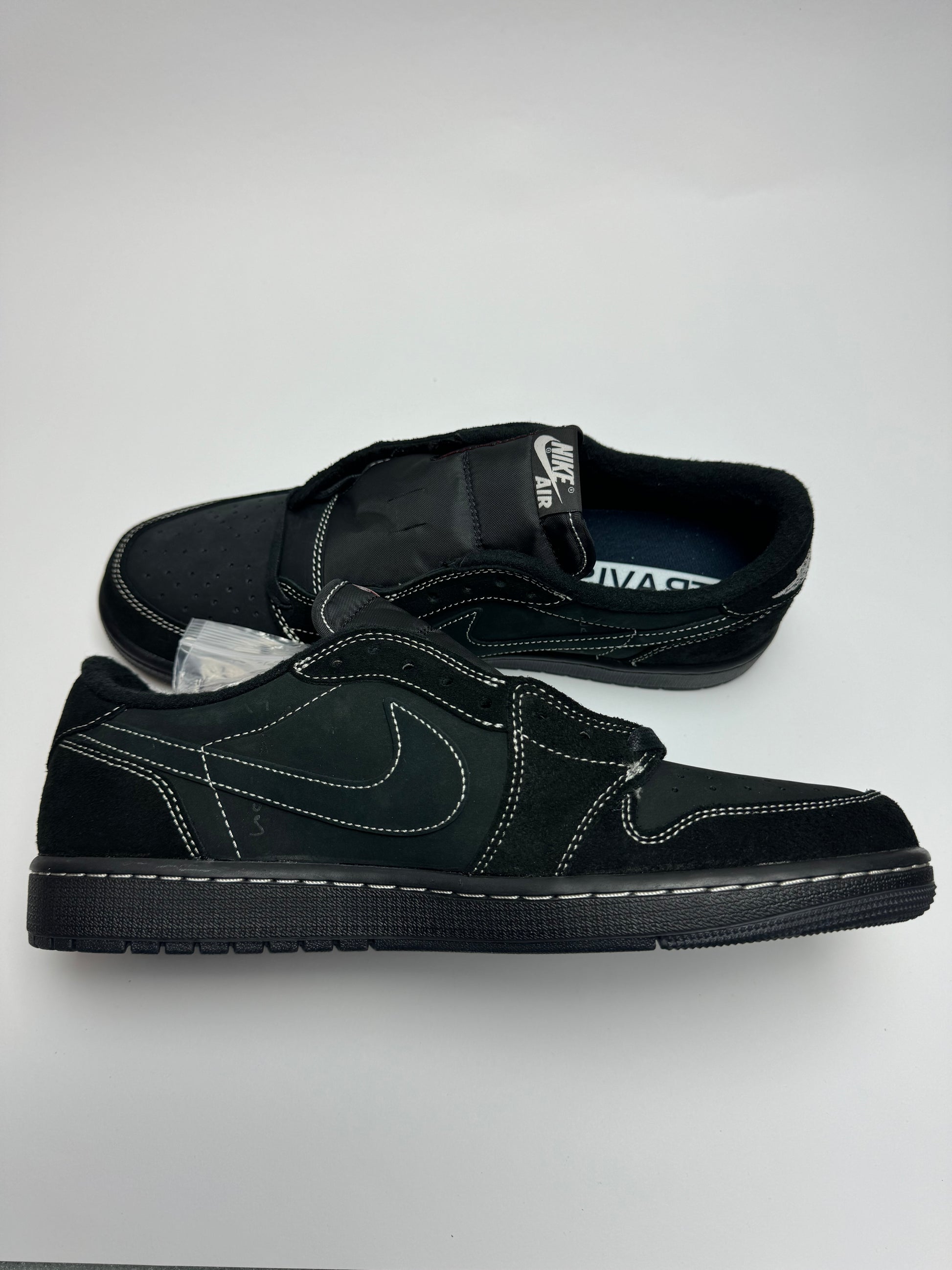 Travis Scott AJ1 Low Black Phantom – linke Außenseite mit zurückgesetztem Swoosh und kontrastreicher weißer Ziernaht