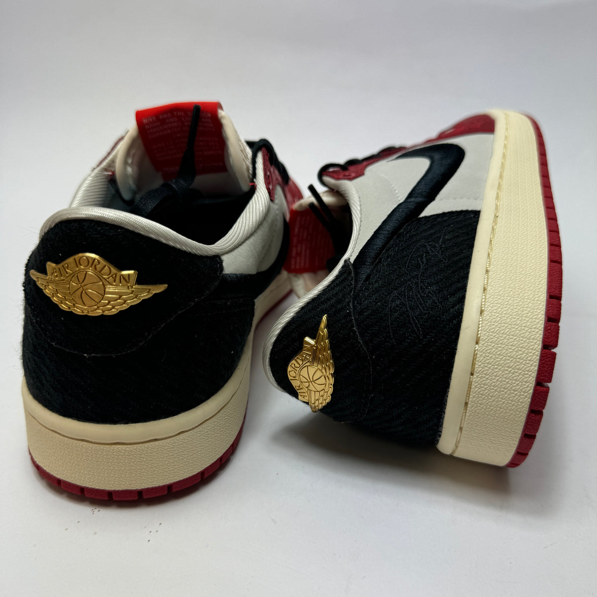Rückansicht des Trophy Room x Air Jordan 1 Low OG Away mit goldenem Wings-Logo und schwarzen Fersenelementen