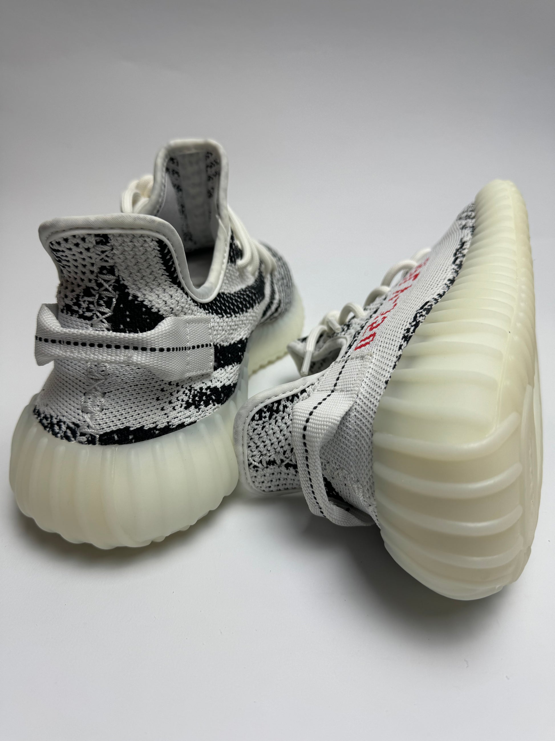 Rückansicht des Sneakers – Zebraboot mit stapelnder Boost-Midsole, semi-transparenter Gummisohle und rotem Akzent