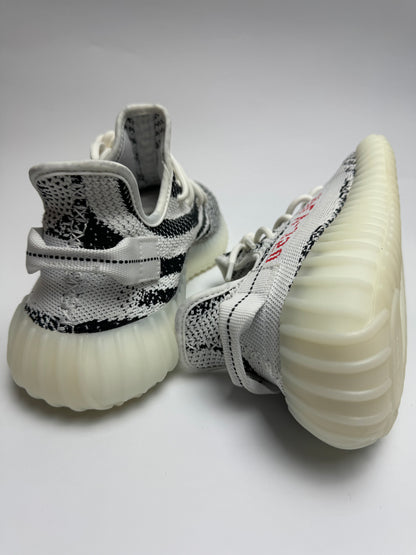 Rückansicht des Sneakers – Zebraboot mit stapelnder Boost-Midsole, semi-transparenter Gummisohle und rotem Akzent
