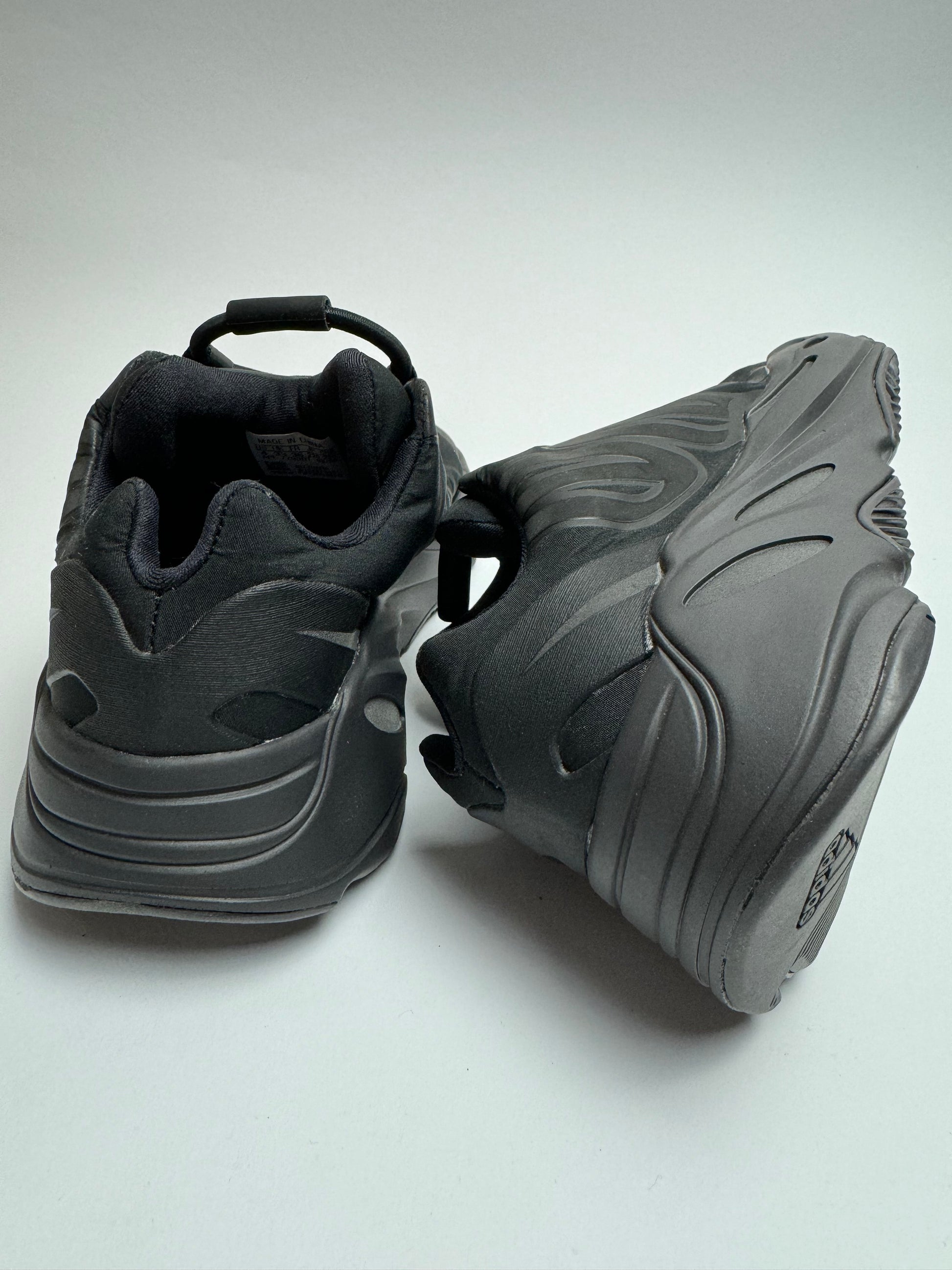 Rückansicht des Sneakers – Yeezy 700 MNVN Triple Black mit schwarzer Boost‑PU‑Midsole und strukturierter Sohle